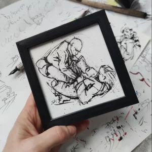 a hand holding a framed picture of a man drawing